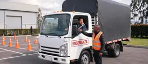 Instructor explica la revisión de espejos de un camión rígido en un patio de prácticas de Bogotá