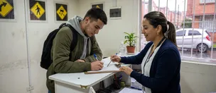 Alumno firma el formulario de matrícula en la recepción de la sede, atendido por una asesora