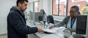 Usuario entrega documentos en una ventanilla de atención para un trámite de licencia
